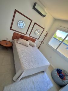 a bedroom with a large white bed and a window at Sua casa em pdetorres in Passo De Torres