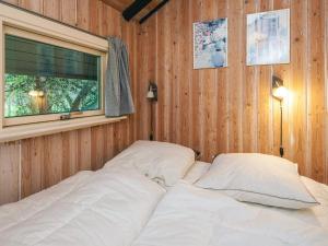 een bed in een houten kamer met een raam bij Secluded Haven in Rindby in Fanø