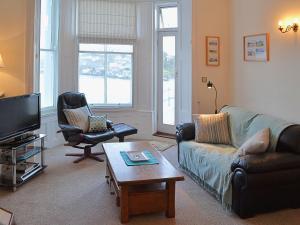 een woonkamer met een bank, stoelen en een tv bij Waterside in Fowey