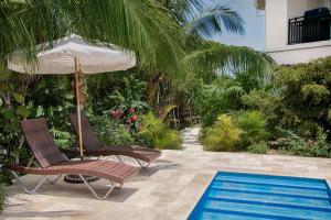 two chairs and an umbrella next to a swimming pool at Karana 4 Bedroom in Long Bay Hills