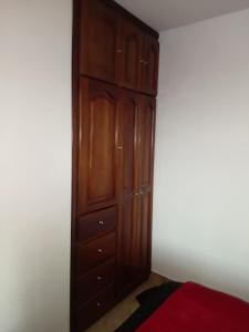 波哥大Habitación cerca del aeropuerto el dorado的一间卧室配有一张位于床边的大型木制橱柜 更多17张照片
