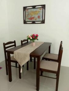 einen Esstisch und Stühle mit einer Blumenvase in der Unterkunft Gee Staycation in Santo Tomas