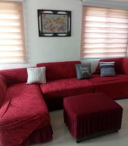 ein Wohnzimmer mit roten Sofas und zwei Fenstern in der Unterkunft Gee Staycation in Santo Tomas + 1 Foto