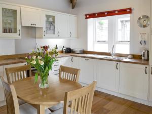 a kitchen with a wooden table with a vase of flowers on it at The Coach House in Whittingham