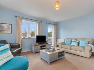 a living room with a couch and a tv at Min Y Traeth By The Beach in Morfa Nefyn