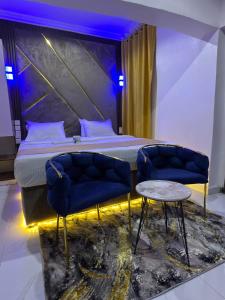 a bedroom with a bed and two chairs and a table at Palazzo Apartments in Ikeja