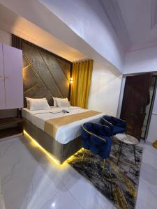 a bedroom with a bed and two blue chairs at Palazzo Apartments in Ikeja