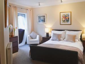 a bedroom with a bed with a chair and a window at Boundary Gallery Cottage in Framlingham