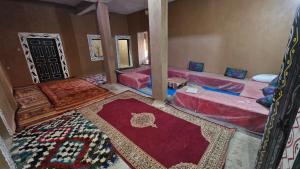 a room with four beds and a rug at Dar salam in Mhamid +38 photos