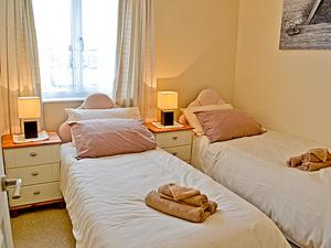 two beds in a room with two lamps and towels at Blue Waves in Perranporth