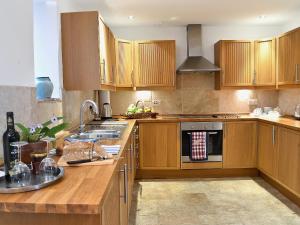 a kitchen with wooden cabinets and a stove top oven at Shaplands Barn in Cold Ashton