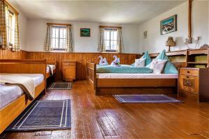 a bedroom with two beds and wooden floors and windows at Vordersattlegghofhütte in Hüttau +49 photos
