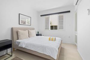 a white bedroom with a bed and a window at The Shores 3 with sea views beautiful sunsets and a breezy balcony in Kralendijk