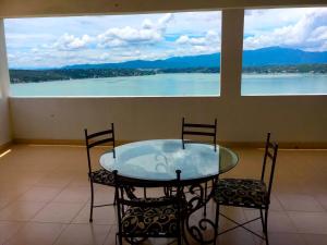 a glass table and chairs with a view of the water at Ameyali Teques in Tequesquitengo