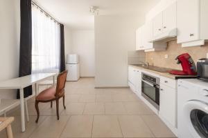 a kitchen with white cabinets and a table with a red appliance at Cénoslocs Aulnay for 6-7 people close to CDG in Aulnay-sous-Bois +22 photos