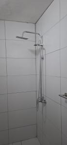 a shower in a bathroom with white tiles at Apart Brumato in Catriel