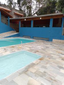 an empty swimming pool in front of a blue building at Chácara Amorim in Mairiporã