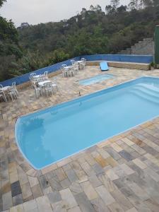 a large blue swimming pool with tables and chairs at Chácara Amorim in Mairiporã