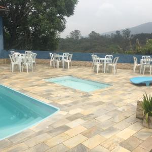 a patio with white chairs and a swimming pool at Chácara Amorim in Mairiporã