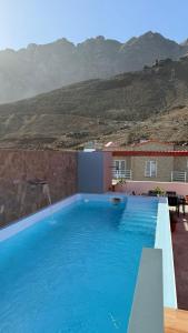 een groot blauw zwembad met bergen op de achtergrond bij Ponta do Sol "A Boa Vida" in Ponta do Sol