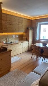 une cuisine avec des armoires en bois, une table et une fenêtre dans l'établissement Olimpic games Cortina, à San Candido
