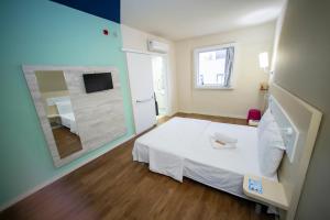 a room with a white bed and a mirror at ibis budget Divinopolis in Divinópolis
