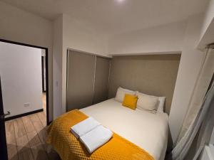a bedroom with a bed with yellow and white pillows at Apartment in Xela Quetzaltengo Interplaza hogar calido in Quetzaltenango