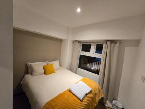 a bedroom with a bed with a yellow blanket and a window at Apartment in Xela Quetzaltengo Interplaza hogar calido in Quetzaltenango