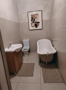 a bathroom with a sink and a tub and a toilet at The Mining Station in Randfontein