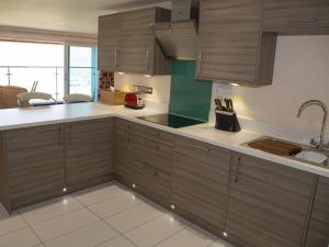 een keuken met houten kasten en witte aanrechtbladen bij Apartment 5 Latitude 51 Westward Ho! in Westward Ho +6 foto's