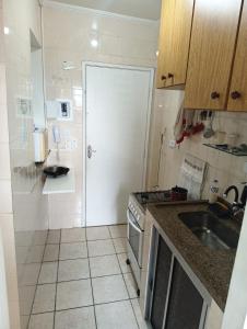 a small kitchen with a sink and a stove at Pousada Praia Grande Apartamento Familiar in Praia Grande