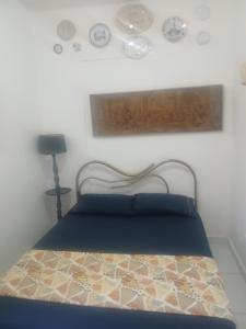 a bedroom with a bed and a lamp and plates on the wall at Alugyel 1 quarto,Aconchegante, ar de nostalgia in Fortaleza