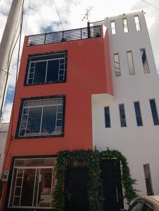 un bâtiment rouge et blanc avec des plantes sur lui dans l'établissement Sultana de los Andes Apartment, à Riobamba