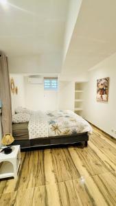 Un dormitorio con una cama y suelo de madera. en Chez Nat&Jo, en Le Bois de Nèfles