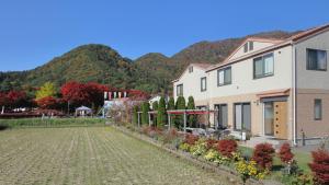 a house with a garden in front of a mountain at Cottage Pastorale in Fujikawaguchiko
