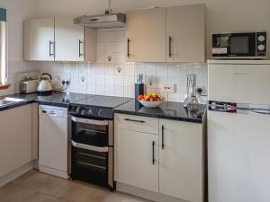 a kitchen with white cabinets and a bowl of fruit at Birch Lodge - 28880 in Torcastle
