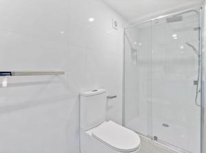 a white bathroom with a toilet and a glass shower at Cozy 1-Bed Studio Near Cafes and Shops in Carnegie +4 photos
