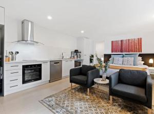 a kitchen and living room with a bed and two chairs at Cozy 1-Bed Studio Near Cafes and Shops in Carnegie