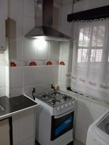 a white kitchen with a stove and a sink at Casa ciudad de la Costa in Ciudad de la Costa