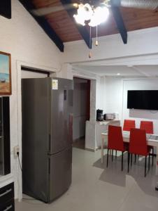 a kitchen with a refrigerator and a table with red chairs at Casa ciudad de la Costa in Ciudad de la Costa