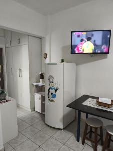 a kitchen with a refrigerator and a tv on a wall at Flat no coração de Guarapari,150 metros da praia com vista encantadora in Guarapari +17 photos