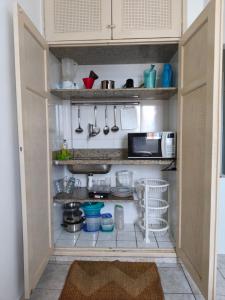 a small kitchen with white cabinets and utensils at Flat no coração de Guarapari,150 metros da praia com vista encantadora in Guarapari