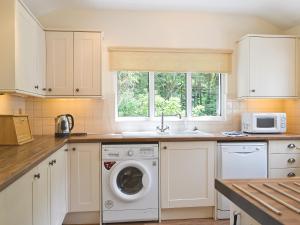 a kitchen with a washing machine and a sink at Joan's Cottage in Braithwaite
