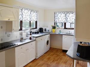 a white kitchen with white cabinets and windows at River View Villa - Cv44 in Saint Cleer
