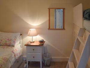 a bedroom with a bed and a table with a lamp at Pear Tree Cottage in Bowness-on-Windermere