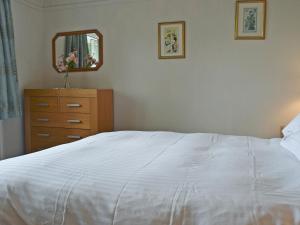 a bedroom with a white bed and a dresser and a mirror at Manesty in Applethwaite