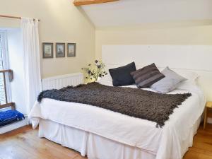 a bedroom with a white bed with black pillows at Shaplands Barn in Cold Ashton
