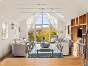 - un salon avec une table, des chaises et une grande fenêtre dans l'établissement Carew Cottage, à Manorbier
