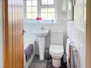 a white bathroom with a toilet and a sink at Pipit Cottage in Burnsall