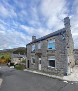 ein altes Steinhaus an der Straßenseite in der Unterkunft Northcliffe - Stylish Stone Cottage - Spa Bath - Peak Views in Bradwell